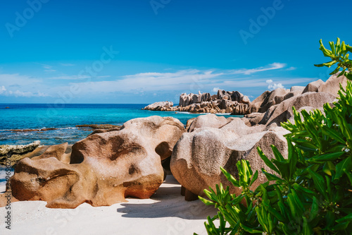 La Digue, Seychelles. Beautiful remote tropical beach with green foliage, unique granite rocks and blue sky