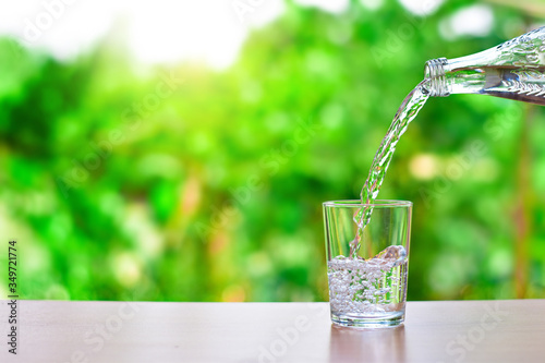Pour water into a glass of water and bubble on natural background with copy space