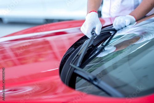 A mechanic is replacing the windshield wipers in the parking lot. The car owner is preparing for the rainy season by changing the windshield wiper rubber.