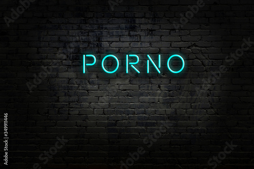 Neon sign with inscription porno against brick wall