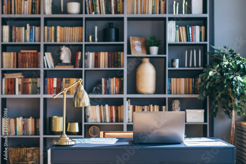 Table with laptop in home office interior.