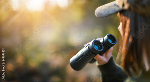 Woman hunter in forest camouflage Uniform with Binoculars. Hunting game concept,