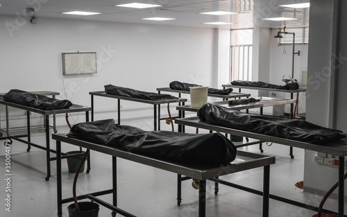 Covered human corpses on tables in a morgue / mortuary waiting for identification, autopsy, burial or cremation. Taken in Armenia, Colombia.