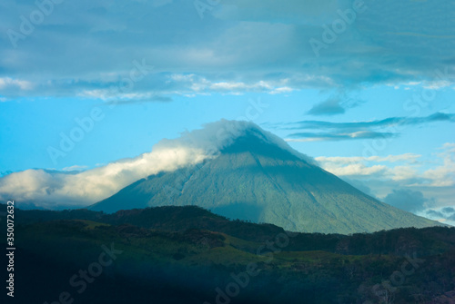 Volcano covered with clouds in Guatemala, forest landscape at imposing sunset on the horizon.