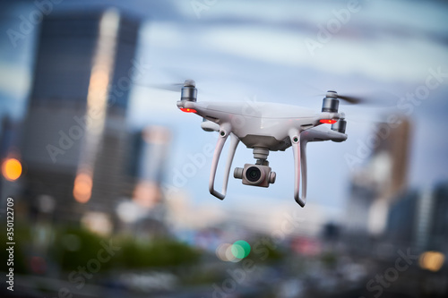 drone quadcopter with digital camera flying at city street