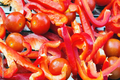 fried and sliced vegetables-tomatoes and red peppers, are cooked on an iron grill for frying. Process of cooking hot tomato sauce for pasta or spaghetti by yourself