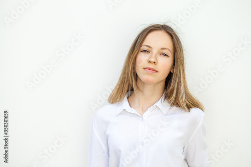 Young blonde girl in white blouse - isolated on white wall background