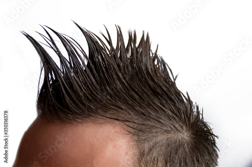 A man with a mohawk turned sideways on a white background