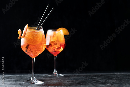 Two glasses of classic italian aperitif aperol spritz cocktail with slice of orange on dark background, traditional summer fresh drink, copy space