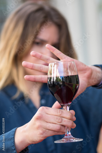 Woman with hand gesture refusing glass of wine or alcohol.