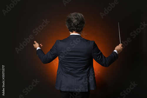 Senior male conductor on dark background