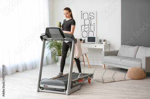 Sporty young woman training on treadmill at home