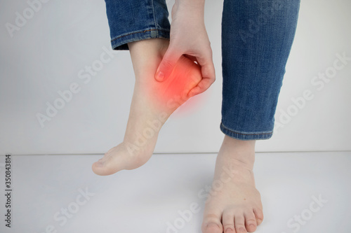 Woman suffering from heel pain. Inflammation or sprain of the tendon in the foot, heel spur, bursitis. The concept of diseases and pains in the leg
