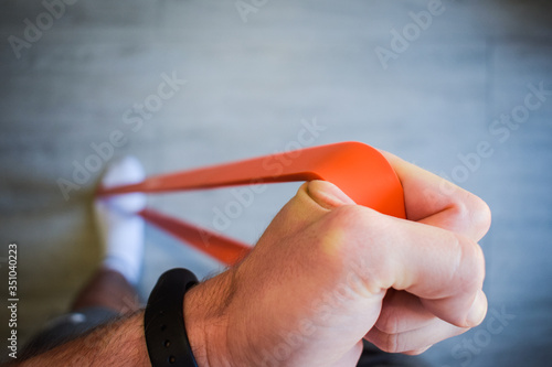 Mano de hombre estirando banda elástica para hacer ejercicio en casa