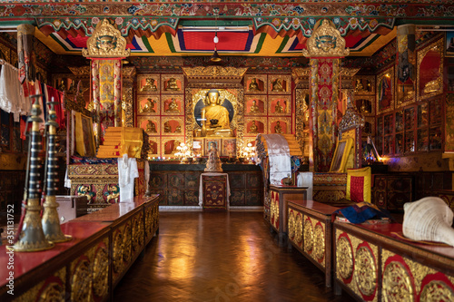 Gompa of one of the Buddhist monasteries, Tibetan Buddhism. A gilded buddha is visible on the altar, in the foreground ritual musical instruments - gyaling and dunkar.