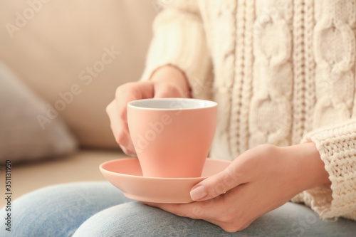Woman with cup of tea at home, closeup