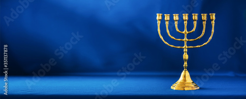 Golden hanukkah menorah on blue background. Jewish holiday banner with copy space. Ancient ritual religious candle menorah