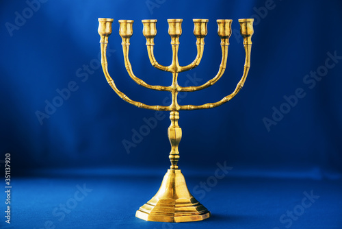 Golden hanukkah menorah on blue background. Jewish holiday banner with copy space. Ancient ritual religious candle menorah