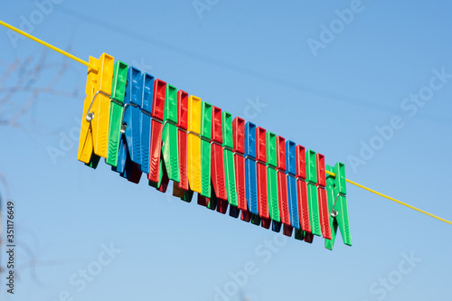 Multicolored plastic clothespins on clothesline rope