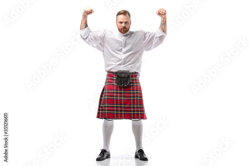 strong Scottish redhead man in red kilt showing fists on white background