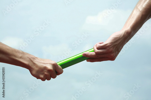 Two men's hands passing the baton in a relay race