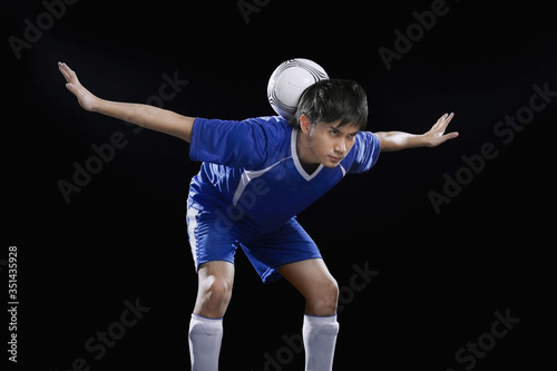 Man balancing soccer ball on the back of neck