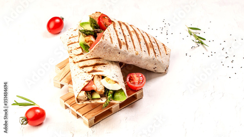 Burritos wraps with asparagus, cherry tomatoes, avocado, chicken fillet on a light background, top view. burrito, mexican food