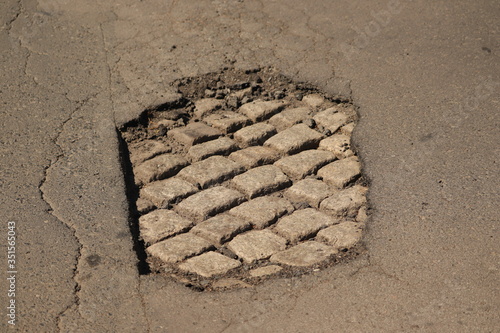 stara kostka brukowa widoczna w dziurze asfaltu