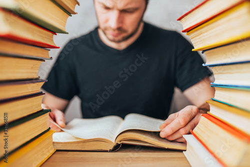 An avid reader - a grown man flips through pages of an old dusty book between stacks of books in an old library