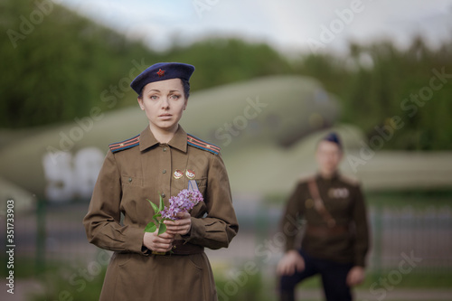 Young adult man and woman in the uniform of pilots of the Soviet Army of the period of World War II. Military uniform with shoulder straps of a major and a cap on his head. Photo in retro style.