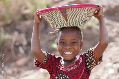 Smiling African Ethnic Girl Outdoors with Food Basket, poverty symbol