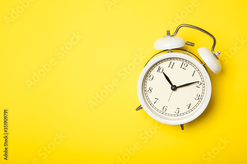 White alarm clock on a yellow background. Top view, place for text.
