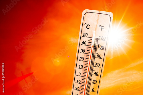 Orange sky with bright sun and thermometer symbolizing climate change and global warming