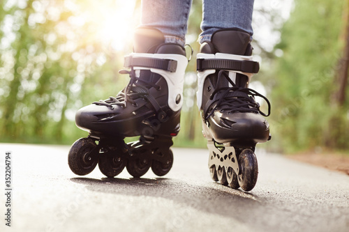 Skilled experienced inline skater making trick, spending free time with pleasure, trying new exercise, having training, rollerblading as hobby, being in middle of road. Rollerskating concept.