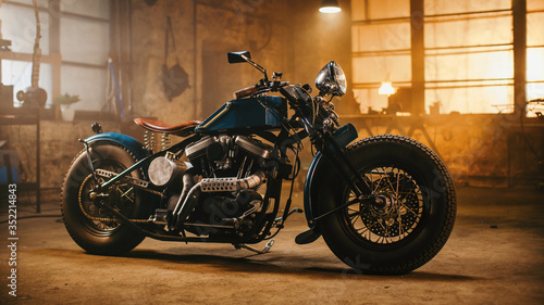 Custom Bobber Motorbike Standing in an Authentic Creative Workshop. Vintage Style Motorcycle Under Warm Lamp Light in a Garage.