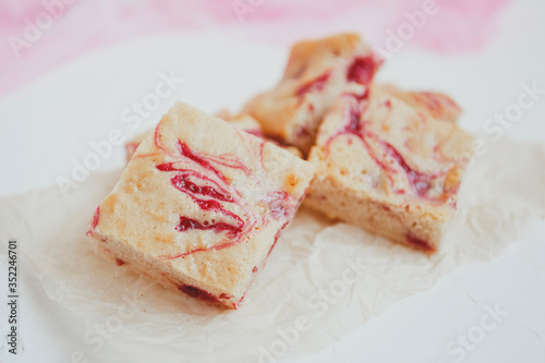 Homemade blondies, made of white chocolate with fresh raspberries, on a light background.