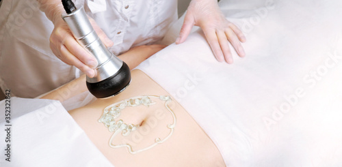 The cavitation procedure closeup. Beautician apparatus for cavitation on the woman's stomach. The concept of skin care face and body