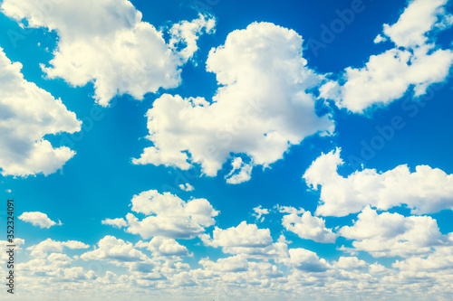 Blue pure sky with many white large clouds. Settled clear weather. Heavenly background, excellent wallpaper. Distance view. Fluffy cumulus clouds. Wide angle. Ozone layer. High cloudiness and forecast