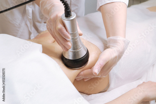 Beautician makes the procedure cavitation of a young beautiful girl. The concept of skin care face and body