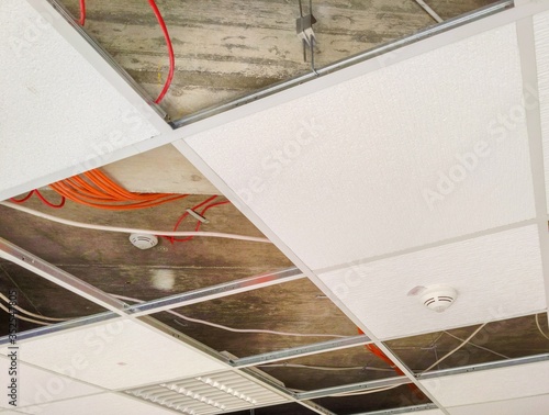 Partially open suspended ceiling, with plenum area and wires visible above acoustic panels and fixtures