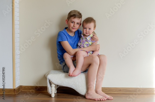 Portrait of two pretty cute children boy and girl. Big brother holding his toddler sister. Kid sibling