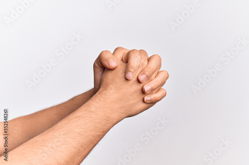 Hand of caucasian young man showing fingers over isolated white background praying with hands clasped, fold fingers religious gesture