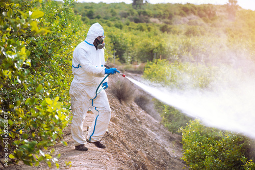 Spray ecological pesticide. Farmer fumigate in protective suit and mask lemon trees. Man spraying toxic pesticides, pesticide, insecticides.