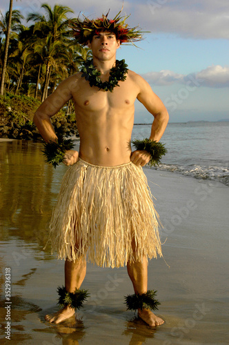 Male hula dancer poses with a power move at sunset by the beach.