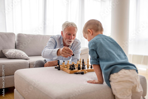 Grandfather and grandson playing chess at home