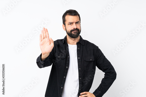 Young man with beard over isolated white background making stop gesture