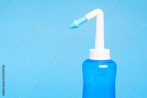 blue water pulse nasal wash bottle on a blue background, nasal irrigation concept