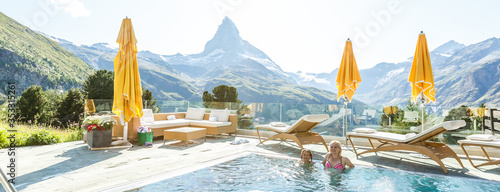 Mother and daughter swimming in outdoor swimming pool in the mountains