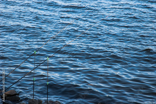 Two spinning rods standing on pods near the river water