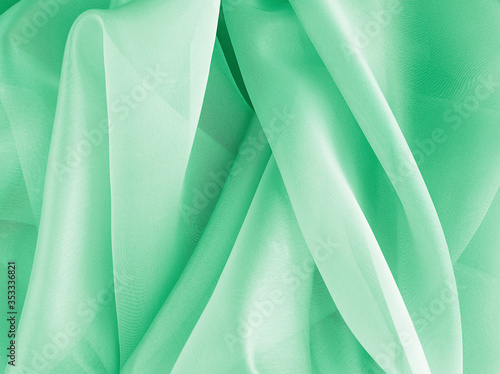 Textiles and textures. Crumpled green organza drapery close-up. The background fabric